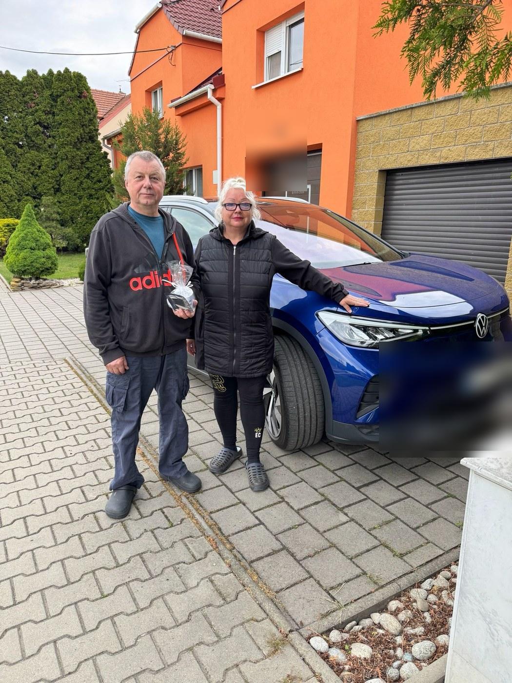 Manželský pár přebírá dovezený elektromobil před domem